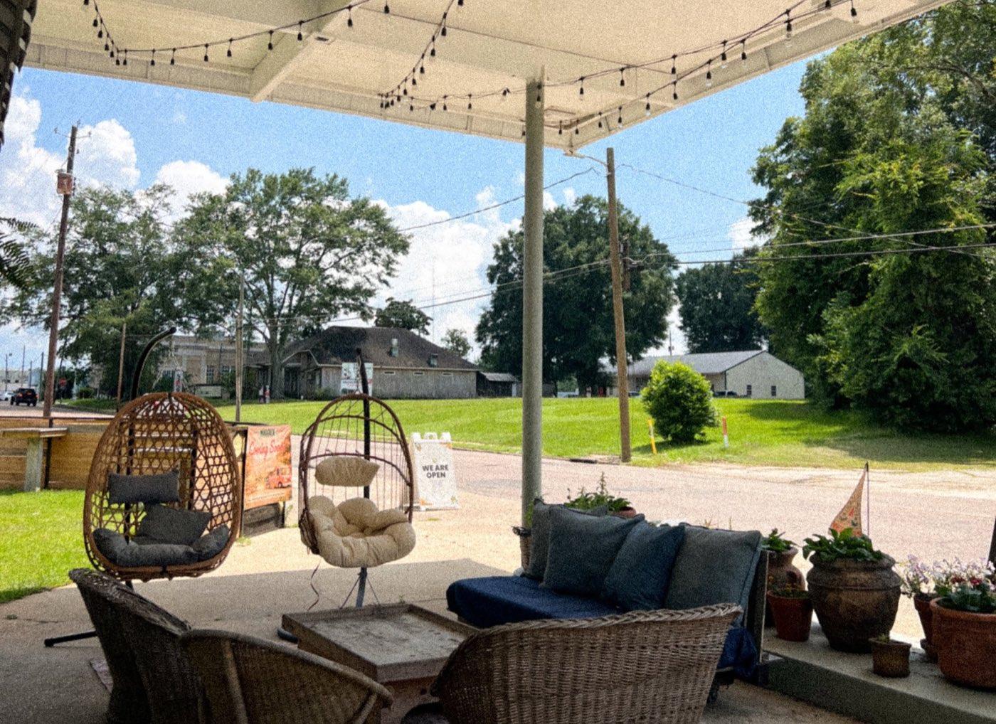 The Re-Filling Station porch — swing chairs, string lights, and the WE ARE OPEN sign on Main Street
